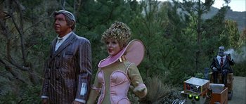 Movie still from “Heartbeeps” (1981), directed by Allan Arkush – A woman dressed in a pink and green costume; Medium shot, Over the shoulder angle