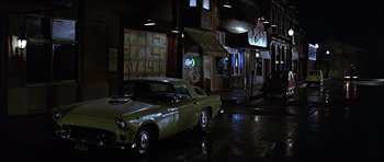 Movie still from “Heartbeeps” (1981), directed by Allan Arkush – An old car parked on the side of the street; Wide shot, High angle