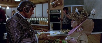 Movie still from “Heartbeeps” (1981), directed by Allan Arkush – A group of people standing around a kitchen; Medium shot, Over the shoulder angle
