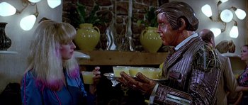 Movie still from “Heartbeeps” (1981), directed by Allan Arkush – Two people dressed up in costumes are holding plates of food; Medium shot, Over the shoulder angle