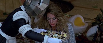 Movie still from “Heartbeeps” (1981), directed by Allan Arkush – A woman holding a plate with a cake on top of it; Close Up shot, High angle