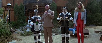 Movie still from “Heartbeeps” (1981), directed by Allan Arkush – A group of people dressed in costumes holding trays of food; Wide shot, Low angle