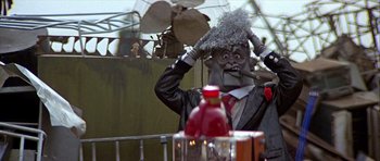 Movie still from “Heartbeeps” (1981), directed by Allan Arkush – A man in a suit and a hat is smoking a pipe; Close Up shot, Low angle