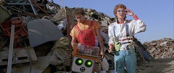 Movie still from “Heartbeeps” (1981), directed by Allan Arkush – Two people standing next to each other in a pile of rubble; Medium shot, Low angle
