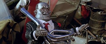 Movie still from “Heartbeeps” (1981), directed by Allan Arkush – A man in a suit and red tie holding a motorcycle handlebars; Medium shot, Low angle