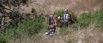 Movie still from “Heartbeeps” (1981), directed by Allan Arkush – A group of people sitting in the grass next to each other; Wide shot, High angle