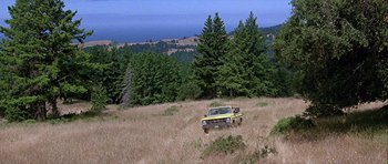 Movie still from “Heartbeeps” (1981), directed by Allan Arkush – An old car is parked in the middle of a field; Extreme Wide shot, High angle