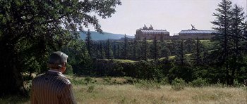 Movie still from “Heartbeeps” (1981), directed by Allan Arkush – A large building on top of a hill in the middle of a forest; Extreme Wide shot, Low angle
