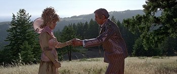 Movie still from “Heartbeeps” (1981), directed by Allan Arkush – An older man and woman shaking hands in a field; Medium shot, Low angle