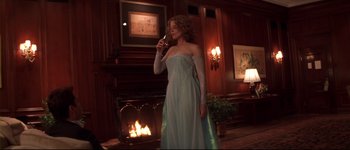 Movie still from “Heartbreakers” (2001), directed by David Mirkin – A woman standing in front of a fireplace holding a candle; Medium shot, Over the shoulder angle