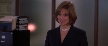 Movie still from “Heartbreakers” (2001), directed by David Mirkin – A person wearing a suit and pearl necklace; Close Up shot, Over the shoulder angle