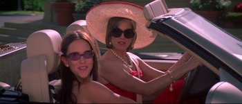 Movie still from “Heartbreakers” (2001), directed by David Mirkin – Two women driving a car in a red dress; Medium shot, High angle