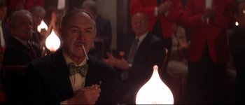 Movie still from “Heartbreakers” (2001), directed by David Mirkin – An older man smoking a cigarette in front of a lit candle; Close Up shot, Low angle