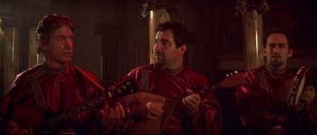 Movie still from “Heartbreakers” (2001), directed by David Mirkin – A man in a red robe playing a guitar; Medium shot, High angle