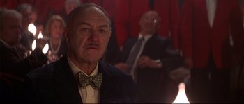 Movie still from “Heartbreakers” (2001), directed by David Mirkin – An older man wearing a suit and bow tie in front of other men; Close Up shot, Low angle