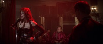 Movie still from “Heartbreakers” (2001), directed by David Mirkin – A group of people sitting in a room with a guitar; Medium shot, Over the shoulder angle