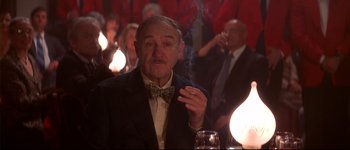 Movie still from “Heartbreakers” (2001), directed by David Mirkin – An older man smoking a cigarette at a party; Medium shot, Low angle