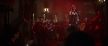 Movie still from “Heartbreakers” (2001), directed by David Mirkin – A group of men and women playing musical instruments in a room; Wide shot, Over the shoulder angle