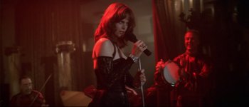 Movie still from “Heartbreakers” (2001), directed by David Mirkin – A woman holding a microphone and singing into a microphone stand; Medium shot, Low angle