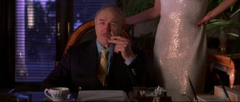 Movie still from “Heartbreakers” (2001), directed by David Mirkin – An older man in a suit and tie sitting at a table; Medium shot, Low angle