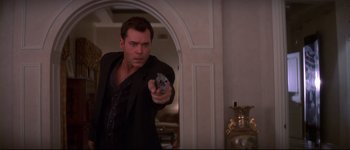 Movie still from “Heartbreakers” (2001), directed by David Mirkin – A man holding a gun in a room; Medium shot, Over the shoulder angle