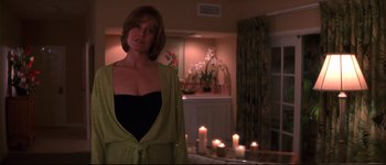 Movie still from “Heartbreakers” (2001), directed by David Mirkin – A woman standing in front of candles in a living room; Medium shot, Low angle
