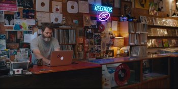 Movie still from “Hearts Beat Loud” (2018), directed by Brett Haley – A man sitting at a desk with a laptop; Medium shot, High angle