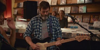 Movie still from “Hearts Beat Loud” (2018), directed by Brett Haley – A man playing an electric guitar in front of a microphone; Medium shot, Over the shoulder angle