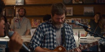 Movie still from “Hearts Beat Loud” (2018), directed by Brett Haley – A man playing an instrument while sitting in front of a microphone; Medium shot, Over the shoulder angle