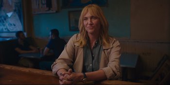 Movie still from “Hearts Beat Loud” (2018), directed by Brett Haley – A woman sitting at a table in front of a painting; Medium shot, Over the shoulder angle