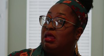 Movie still from “Heaven's Date” (2022), directed by Stevie Fernandez – A person wearing glasses and a head scarf; Close Up shot, Over the shoulder angle