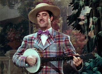 Movie still from “Hello Frisco, Hello” (1943), directed by H. Bruce Humberstone – A man wearing a suit and hat playing a banjo; Medium shot, Low angle
