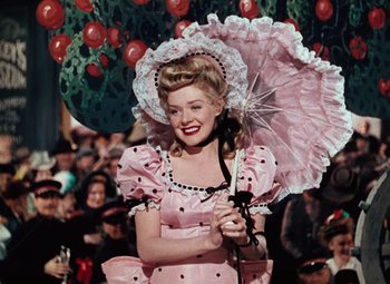 Movie still from “Hello Frisco, Hello” (1943), directed by H. Bruce Humberstone – A woman in a pink dress holding an umbrella; Medium shot, Low angle