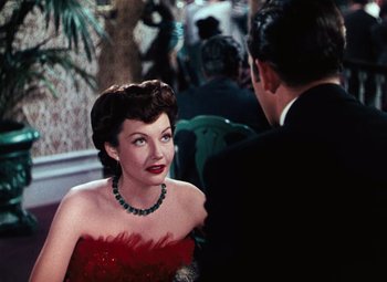Movie still from “Hello Frisco, Hello” (1943), directed by H. Bruce Humberstone – A woman in a red dress talking to a man in a black suit; Medium shot, Over the shoulder angle