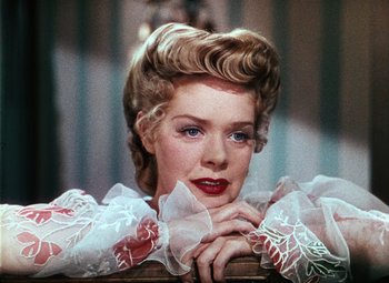 Movie still from “Hello Frisco, Hello” (1943), directed by H. Bruce Humberstone – A woman in a white and red dress leaning on a chair; Close Up shot, Low angle