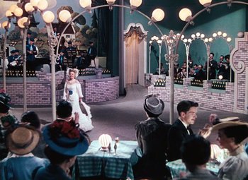 Movie still from “Hello Frisco, Hello” (1943), directed by H. Bruce Humberstone – A group of people sitting in a room with lights; Wide shot, High angle