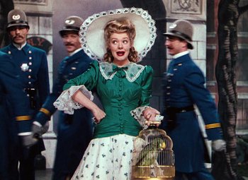 Movie still from “Hello Frisco, Hello” (1943), directed by H. Bruce Humberstone – A woman in a green dress holding a bird in a cage; Medium shot, Low angle