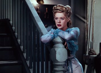 Movie still from “Hello Frisco, Hello” (1943), directed by H. Bruce Humberstone – A woman leaning on the railing of a staircase; Medium shot, Low angle