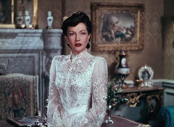 Movie still from “Hello Frisco, Hello” (1943), directed by H. Bruce Humberstone – A woman in a white dress standing in front of a painting; Medium shot, Over the shoulder angle