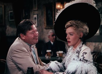 Movie still from “Hello Frisco, Hello” (1943), directed by H. Bruce Humberstone – An older man sitting next to an older woman in front of drinks; Medium shot, Over the shoulder angle