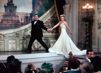 Movie still from “Hello Frisco, Hello” (1943), directed by H. Bruce Humberstone – A man and a woman on a stage in front of an audience; Wide shot, Low angle