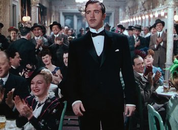 Movie still from “Hello Frisco, Hello” (1943), directed by H. Bruce Humberstone – A man in a tuxedo standing in front of an audience; Medium shot, Low angle