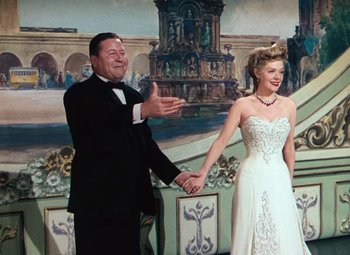 Movie still from “Hello Frisco, Hello” (1943), directed by H. Bruce Humberstone – A man and a woman holding hands in front of a painting; Medium shot, Low angle