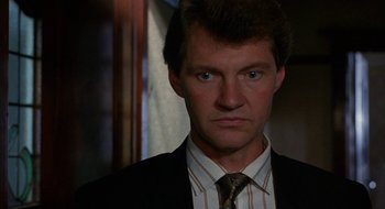 Movie still from “Hellraiser” (1987), directed by Clive Barker – A person wearing a suit and tie; Close Up shot, Low angle