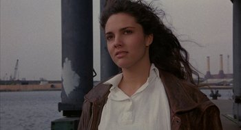 Movie still from “Hellraiser” (1987), directed by Clive Barker – A woman with long brown hair wearing a white shirt and a brown jacket; Close Up shot, Low angle