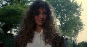 Movie still from “Hellraiser” (1987), directed by Clive Barker – A woman with long curly hair posing for a picture; Close Up shot, Over the shoulder angle