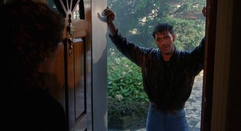 Movie still from “Hellraiser” (1987), directed by Clive Barker – A man holding up a key to a door; Medium shot, Over the shoulder angle
