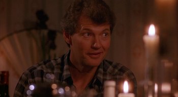 Movie still from “Hellraiser” (1987), directed by Clive Barker – A man sitting in front of a lit candle in a room; Close Up shot, Low angle