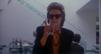Movie still from “Hellraiser” (1987), directed by Clive Barker – A woman in black jacket holding a glass of water; Close Up shot, Low angle