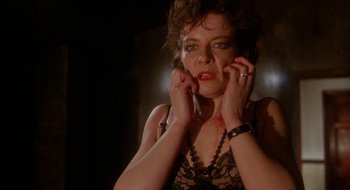 Movie still from “Hellraiser” (1987), directed by Clive Barker – A woman in a black top is talking on a phone; Close Up shot, Low angle